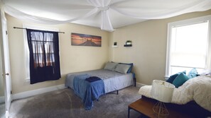 A bedroom with a bed, a window, a painting, and a ceiling fan. - Evanston BnB (Detroit)