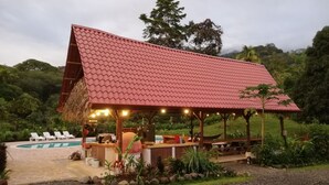 Ein überdachter Außenbereich mit Pool, Liegestühlen und Bar.