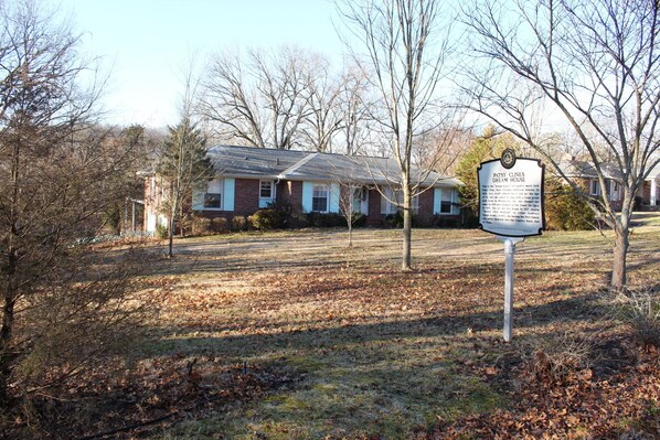 A house with a sign in front, surrounded by trees and a grassy yard. - Patsy Cline's Dream Home (Goodlettsville)