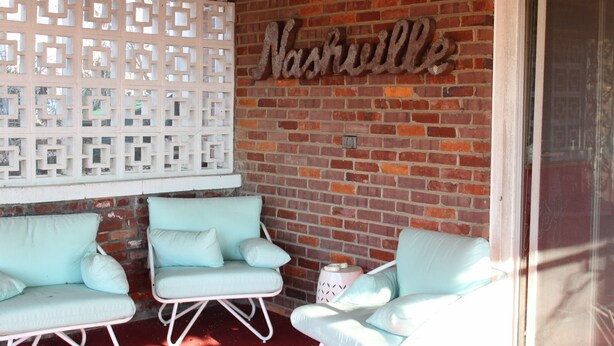 A covered patio area with two light blue chairs and a decorative white lattice wall.