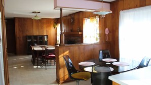 A dining area with a wooden interior, a brick fireplace, and a kitchen area with a pink telephone.