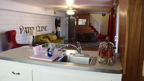 A kitchen with a sink, a countertop with a dish rack, and a wall with a poster.