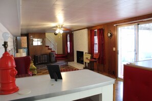 A spacious living room with a fireplace, a staircase, and a large window. - Patsy Cline's Dream Home (Goodlettsville)