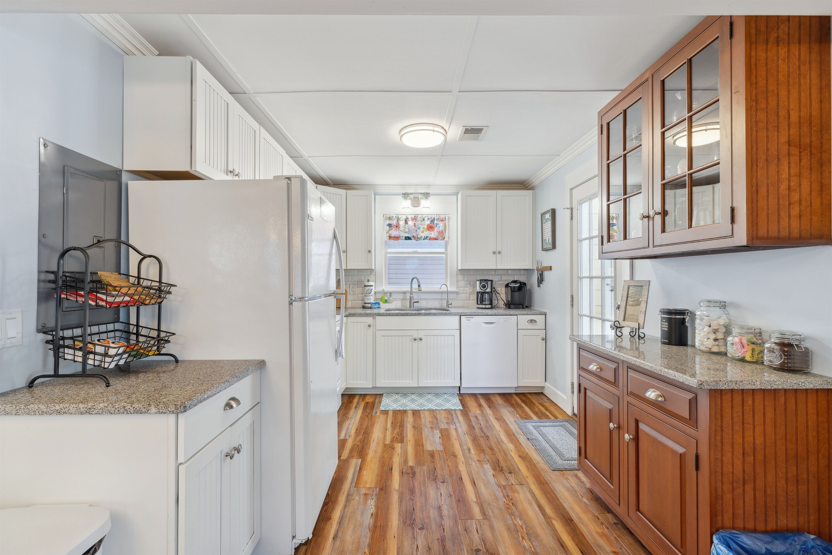 A kitchen with white cabinets, a wooden countertop, a refrigerator, and a sink.
