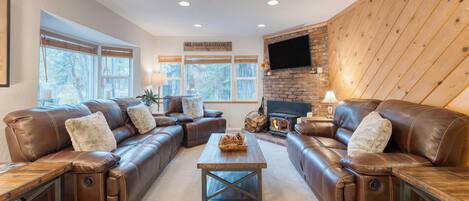 A cozy living room with leather sofas, a wooden coffee table, and a fireplace.