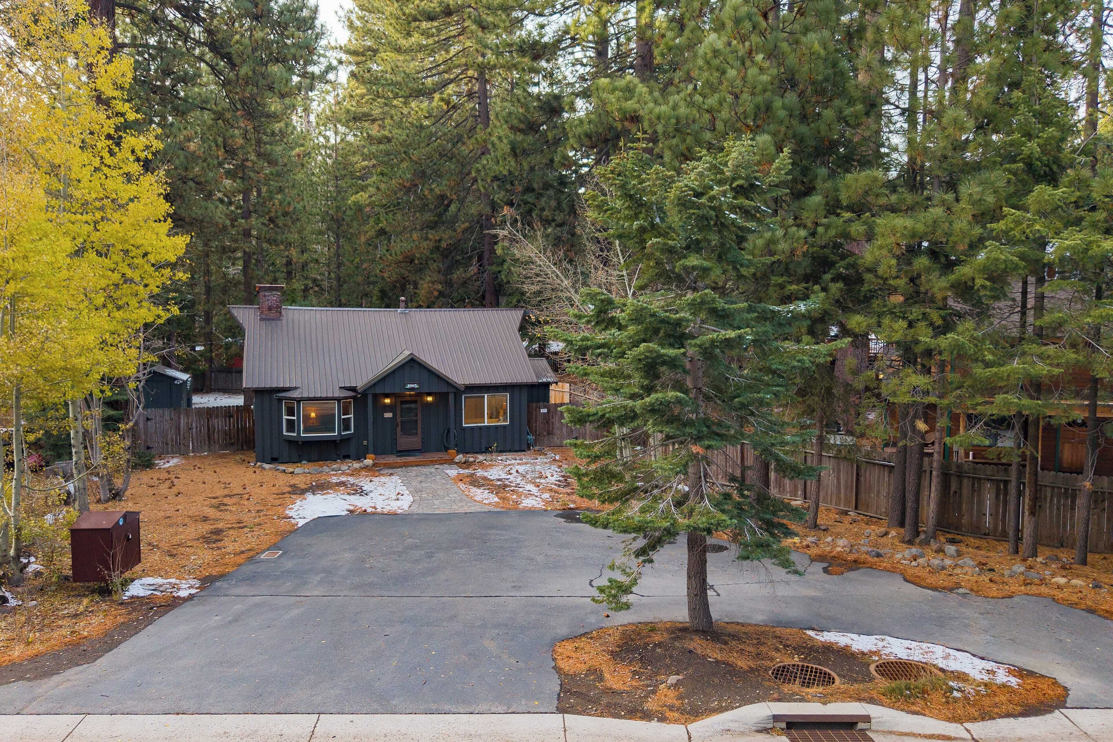 A two-story house with a dark exterior, a front porch, and a driveway leading to the garage.