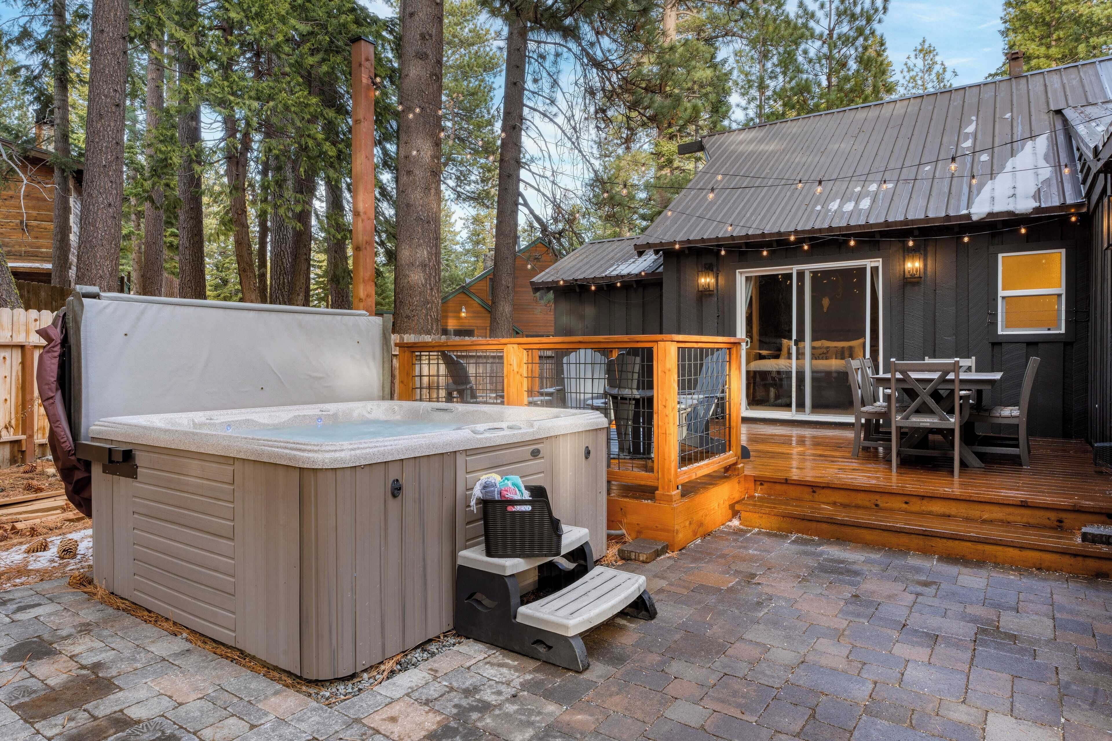 A hot tub with a wooden deck and a covered patio area.