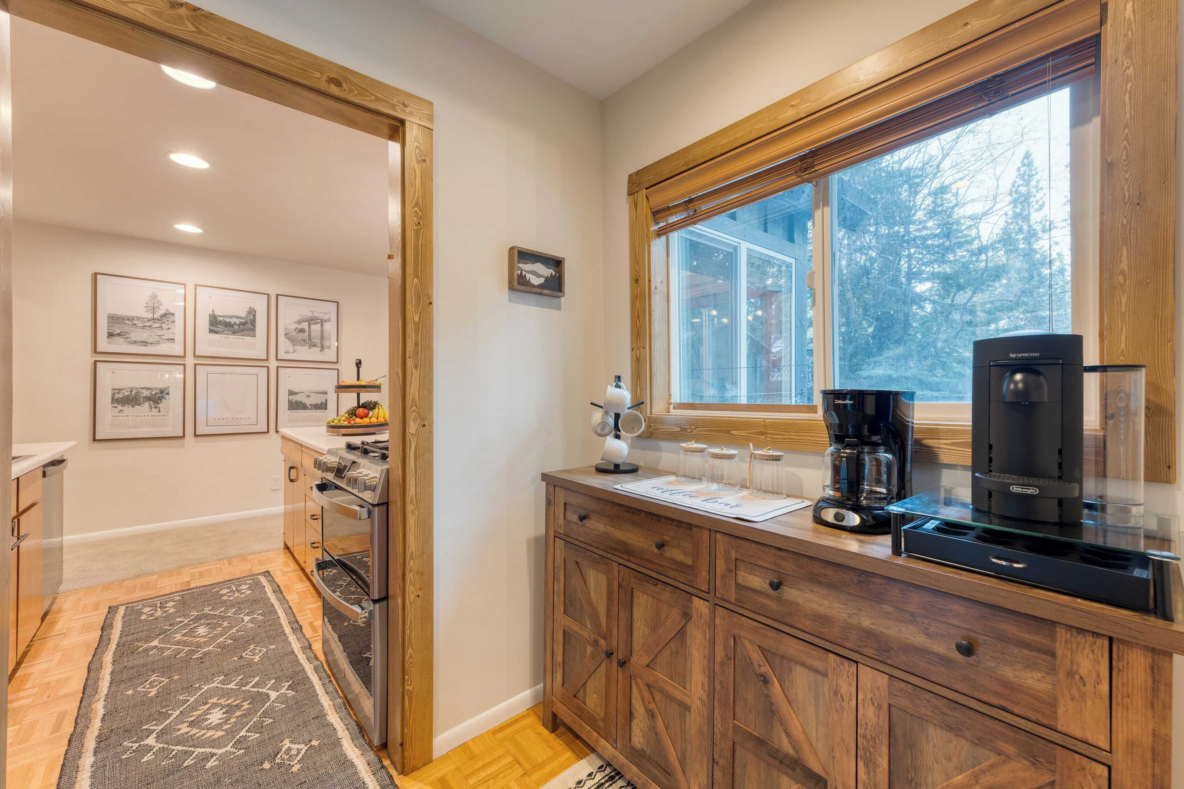 Une cuisine moderne avec des meubles en bois, une machine à café et une fenêtre donnant sur des arbres.