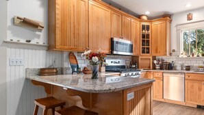 A kitchen with wooden cabinets, a granite countertop, a stove, and a sink.
