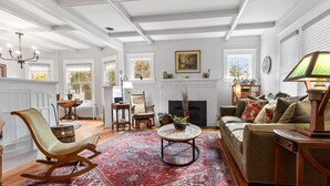 A spacious living room with a fireplace, a large window, and a patterned rug.