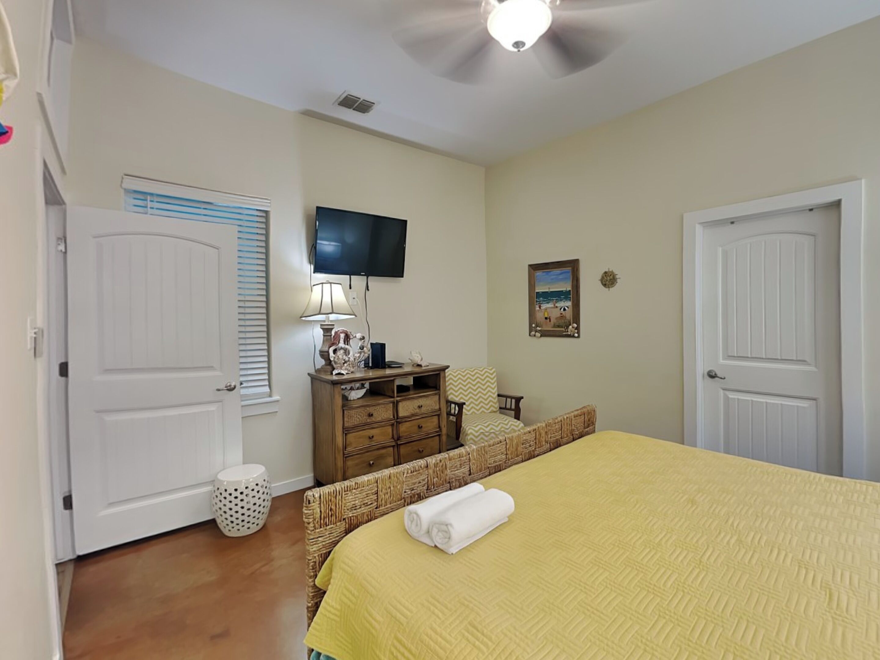 A bedroom with a bed, a desk, a chair, a television, and a door.