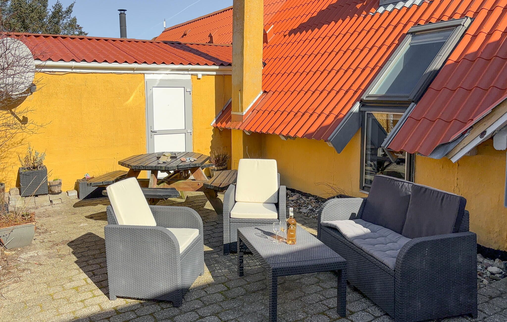 Eine Terrasse im Freien mit Korbmöbeln, einem Tisch und einer Spirituosenflasche.