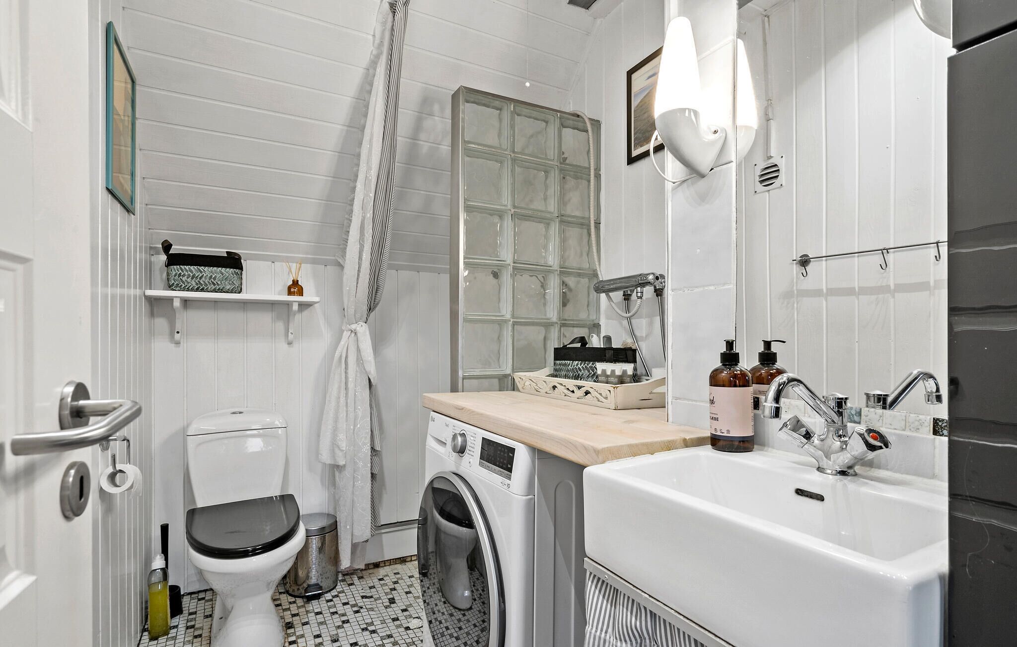 Une salle de bain moderne et compacte, équipée de toilettes, d’un lave-linge et d’un lavabo.