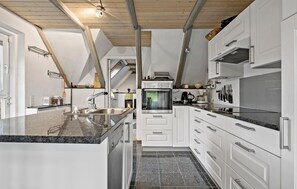 Una cocina moderna con armarios blancos, una encimera de granito y un horno empotrado.