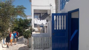 Una calle estrecha con edificios blancos y puertas azules, que conduce a una escalera.