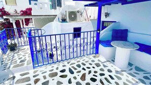 Un patio con piso de mosaico, una puerta azul y un edificio blanco con toldo azul.