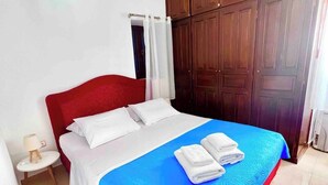 Un dormitorio con cama, mesita de noche, armario de madera y candelabro.