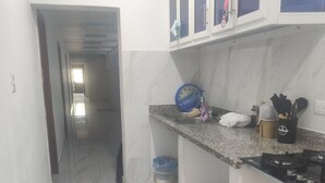 Eine Küche mit weißen Schränken, einer Spüle, einem Herd und einer blauen Uhr an der Wand.