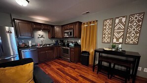 Una cocina funcional con armarios de madera, refrigerador, microondas y cafetera.