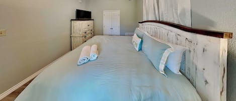 Een slaapkamer met een bed, een plafondventilator, een kledingkast en een televisie.