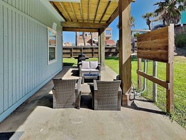 An outdoor patio with wicker furniture, a grill, and a view of a residential area.