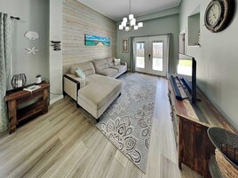 A spacious living room with a sofa, a coffee table, a TV, and a patterned rug.