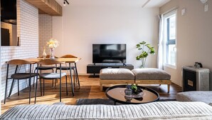 A modern living room with a TV, dining table, and seating area. - ZABO HILLS 203 (Sapporo)