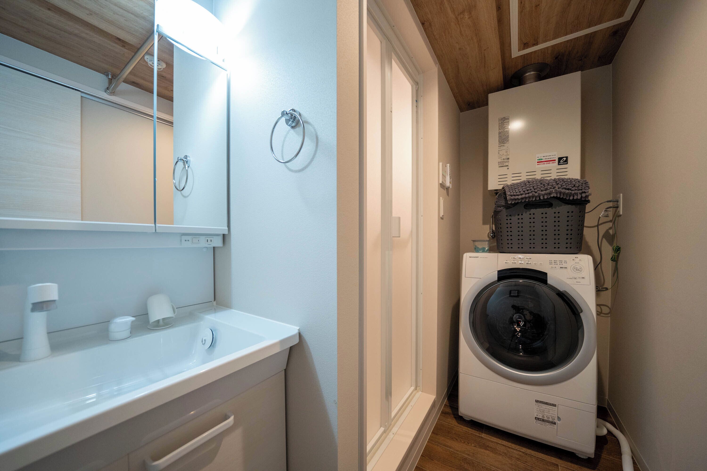 A compact laundry room with a washing machine, a sink, and a mirror.
