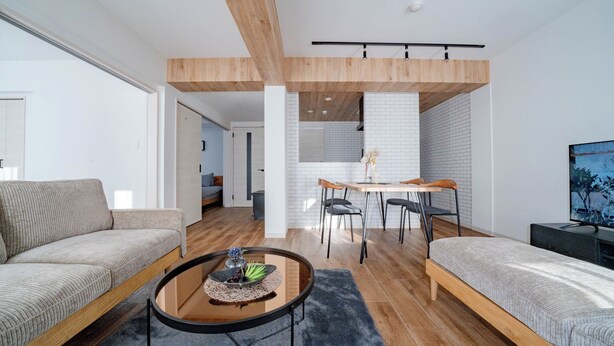 A modern living room with a sofa, a round coffee table, a dining area with a table and chairs, and a bed. - ZABO HILLS 203 (Sapporo)