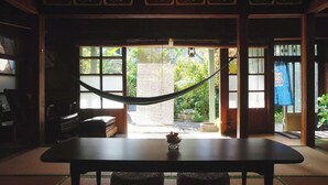 A traditional Japanese room with tatami flooring, a low table with a woven mat, and a hammock.