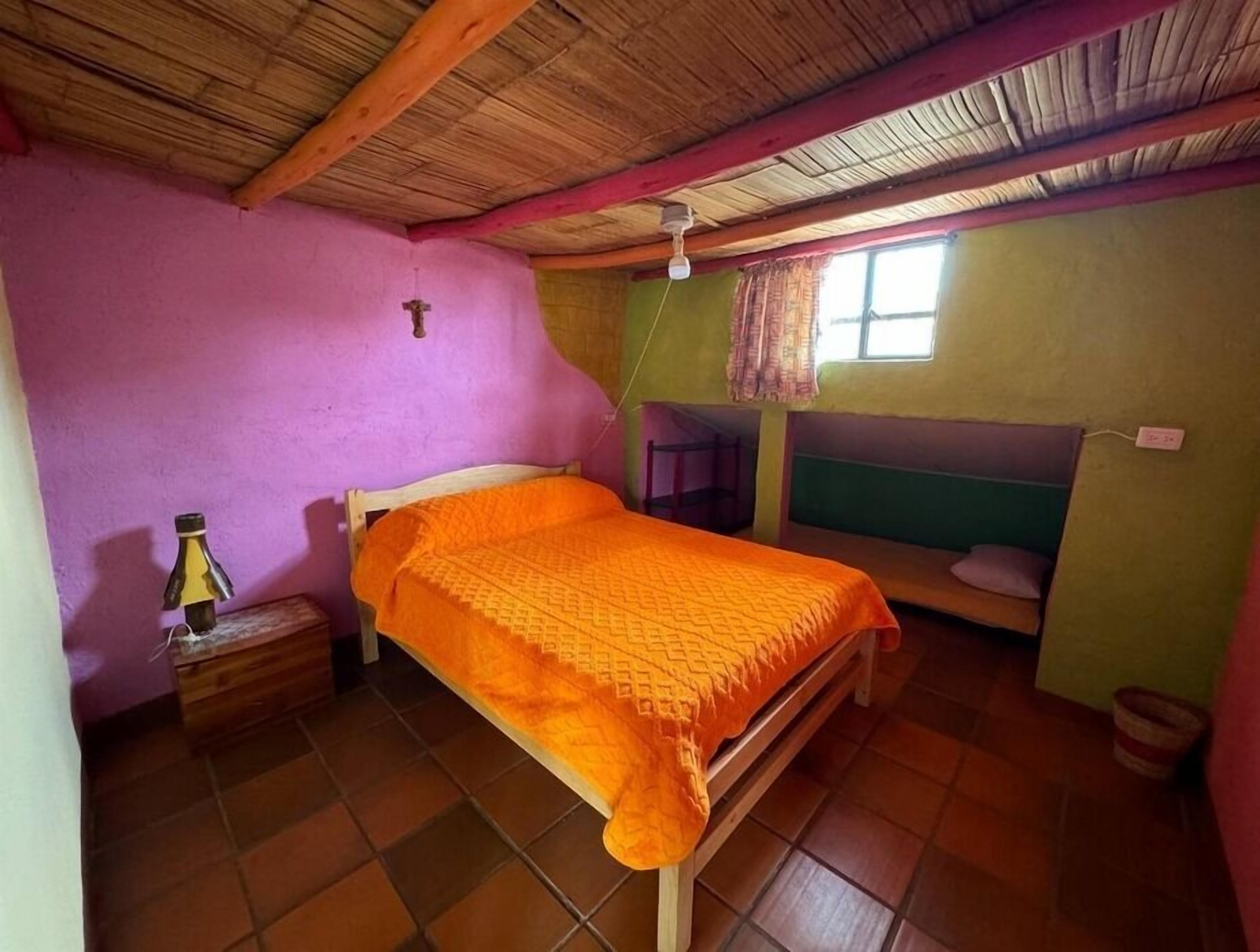 A bedroom with a bed, a small table, a window, and a bunk bed.