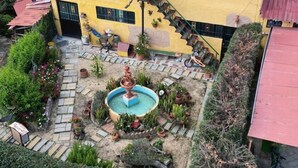 Een binnentuin met een centrale fontein, omgeven door plantenpotten en een klein zitgedeelte.