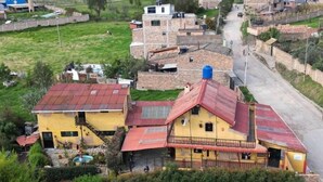 A two-story house with a red roof and a balcony.