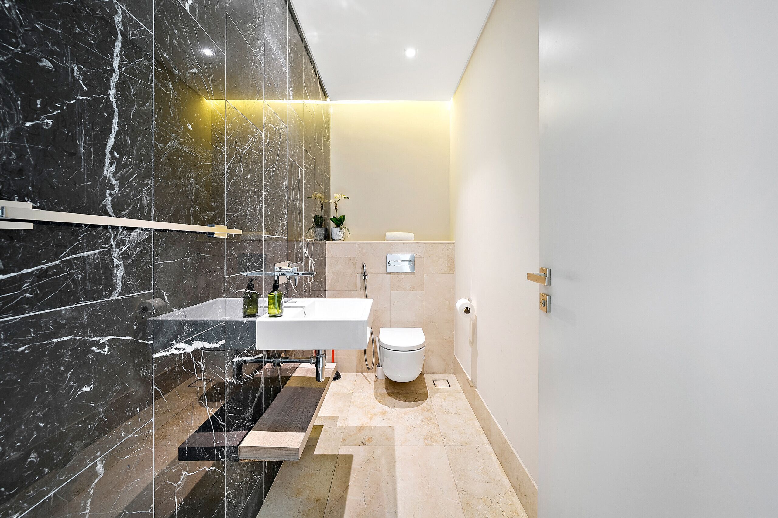 Une salle de bain moderne avec un meuble-lavabo en marbre, des toilettes et un espace douche.