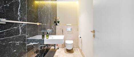 Une salle de bain moderne avec un meuble-lavabo en marbre, des toilettes et un espace douche.