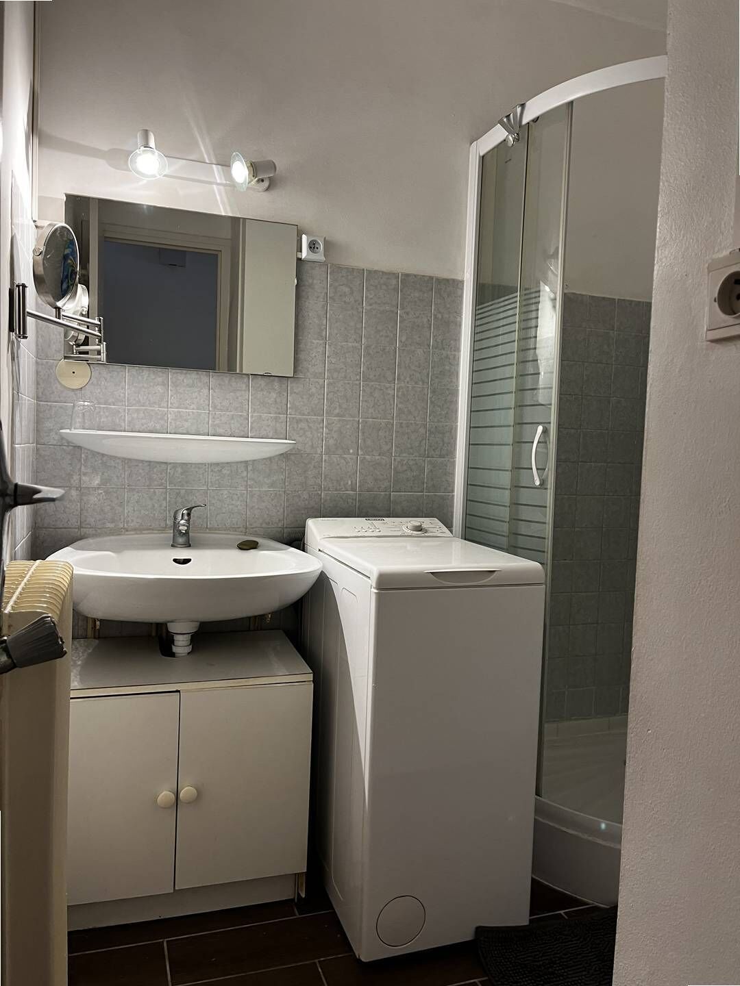 Een moderne badkamer met een witte wastafel, spiegel en een ingebouwde wasmachine.