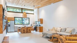 Une cuisine moderne avec des meubles en bois, un coin repas avec une table et des chaises, et un salon avec un canapé et une table basse.