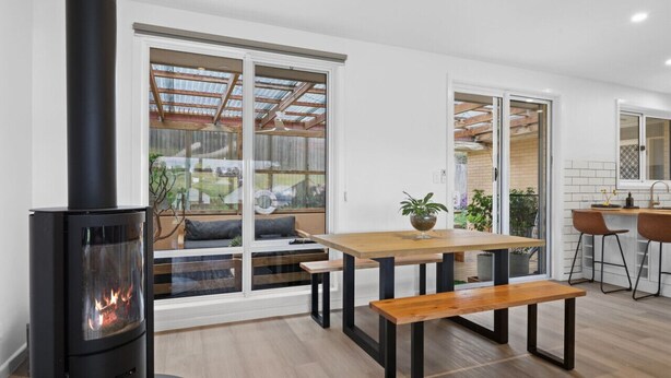 A modern kitchen with a central island, large windows, and a built-in wood stove. - 3 bedroom, pet friendly home CBD (Warrnambool)