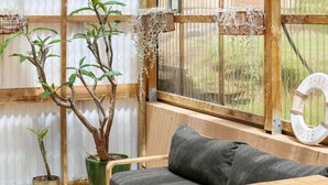 A wooden bench with a cushion, a potted plant, and a decorative wreath on a window sill. - 3 bedroom, pet friendly home CBD (Warrnambool)