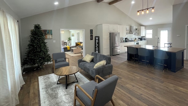 A spacious living area with a wooden floor, a large gray sofa, a coffee table, and a Christmas tree. - Charming countryside home in the heart of Amish Country (Fredericktown)
