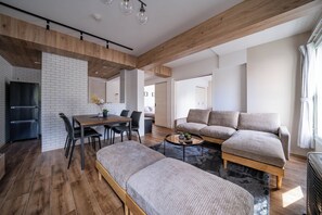 Uma sala de estar moderna com sofá, mesa de centro e área de jantar com cadeiras e mesa.