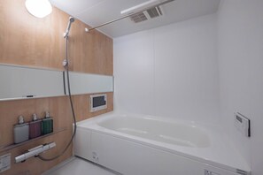 A modern bathroom with a large white bathtub, a wooden vanity, and a built-in showerhead.