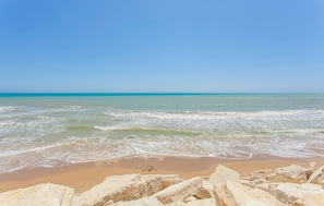 A beach with clear blue water, sandy shore, and large rocks in the foreground. - 3 bedroom gorgeous home in Comiso (Comiso)
