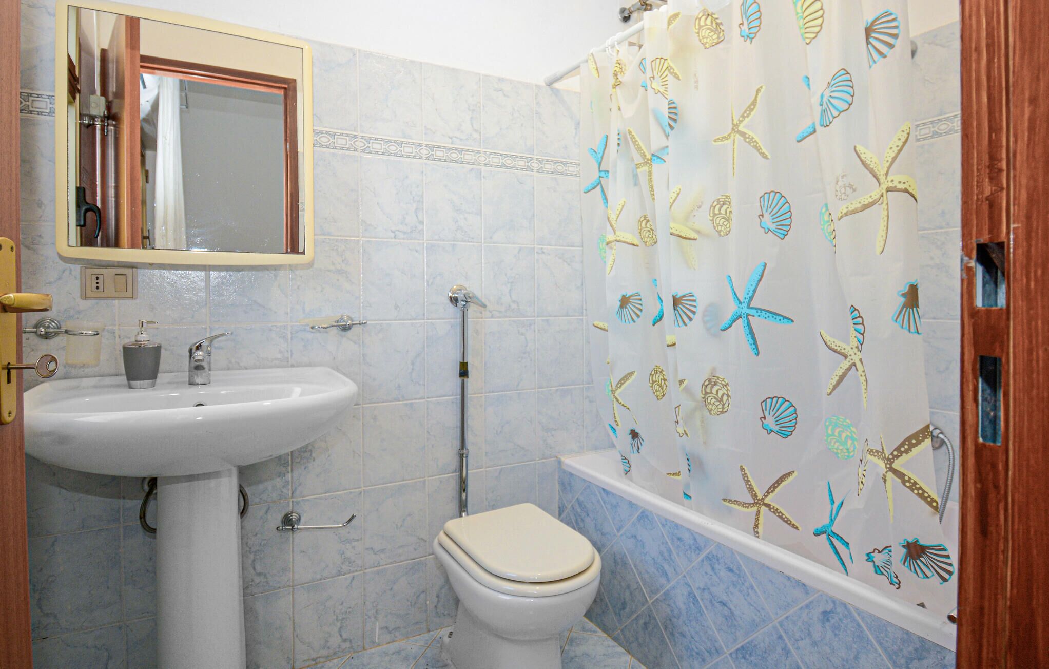 Casa de banho com lavatório branco, sanita e banheira.