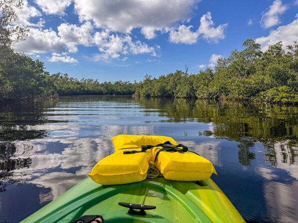 Un kayak vert avec des gilets de sauvetage jaunes sur l’eau.