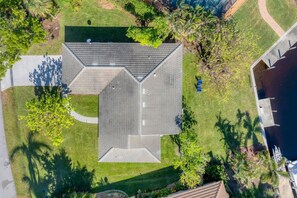 A residential building with a sloped roof, surrounded by a well-maintained lawn and trees.