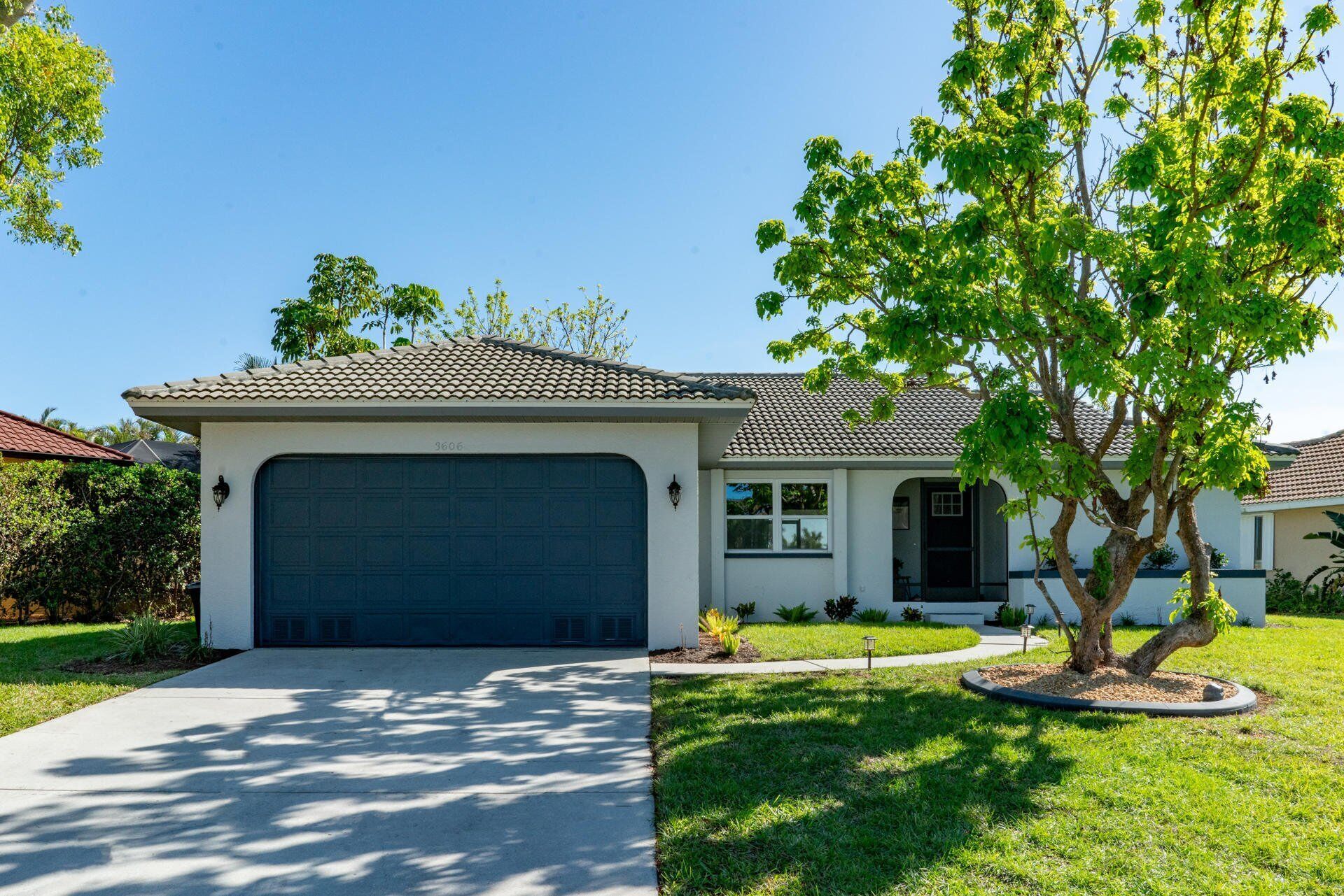 A single-story house with a garage, a front yard, and a tree.