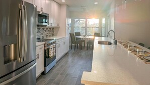 Una cocina moderna con electrodomésticos de acero inoxidable, una isla grande y un comedor con vistas.