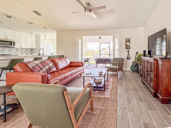 A spacious living room with a leather sofa, a coffee table, and a television on a wooden cabinet.