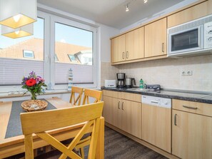 Eine moderne Küche mit Holzausstattung, integriertem Mikrowellenherd und einem Essbereich mit Tisch und Stühlen.